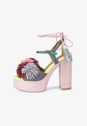 Meer gekleurde platformhakken met een roze, met studs versierde zool; groene band met bloemmotieven in rood en zilver; roze enkelbandjes.