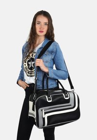 Zwart-witte gestructureerde tas met een textuurafwerking, met zilverkleurige hardware, dubbele handgrepen en een afneembare schouderriem.