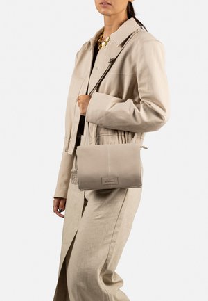 Beige Leder Crossbody Tasche mit glatter Textur und rechteckiger Form. Verfügt über ein dezentes Logo-Patch und einen kurzen Tragegurt.