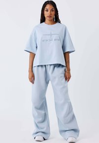 Lichtblauwe oversized t-shirt met subtiele logo-borduring en bijpassende wijde sweatpants. Zachte textuur, katoenmix materiaal.