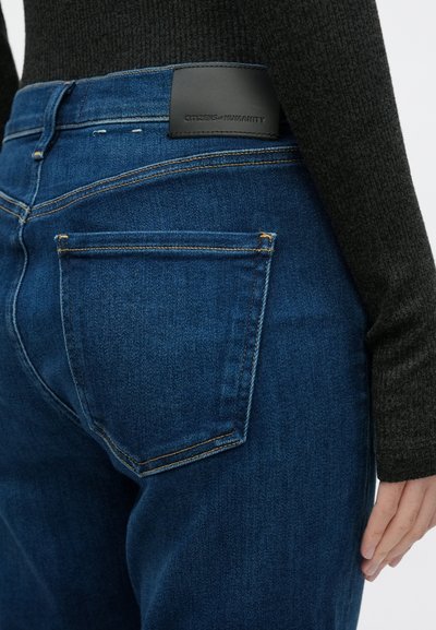 Σκούρο μπλε τζιν παντελόνι από denim με δερμάτινο λογότυπο στη μέση, διαθέτει πίσω τσέπη και ορατές ραφές.