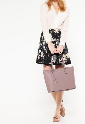 Vaaleanpunainen nahka-tote-laukku, jossa on suorakulmainen muoto, kaksinkertaiset pääkahvat ja minimaaliset metalliosat. Silkinen pinta, jossa on hienovarainen kohokuvioitu logo.