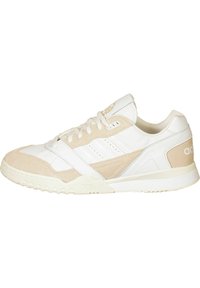 Vita och beige idrottssko med mocka och lädermaterial, med rund tå, snörning och texturerad gummisula.