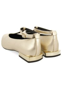 Bailarinas metálicas doradas con punta redonda, tira en el tobillo y un tacón grueso con detalles dorados. Textura suave con mínimos detalles de costura.