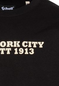 T-shirt in cotone nero con scritto in bianco audace "NEW YORK CITY SCHOTT 1913" sul fronte. Collo a coste, texture morbida.