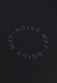 Zwarte textuurstof met een ronde, reliëf logo waarin de tekst "NOISY MAY" in een cirkel is gerangschikt, subtiele glans op de letters.