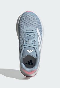 Zapatilla deportiva azul clara con parte superior de malla, cordones en el mismo tono y tres rayas blancas. Detalle rosa en el talón trasero, suela de goma y collar acolchado.