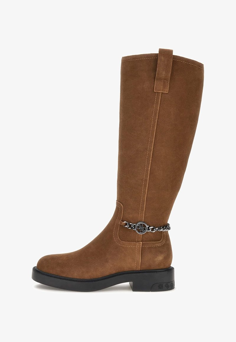 Brūni zamšādas cepures līdz ceļiem ar noapaļotu purngalu, saliktu papēdi un dekoratīvu sudraba ķēdes akcentu ap potīti. Gluda, minimāla dizaina.