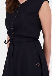 Abito navy con bottoni, scollatura a V, maniche corte e vita aderente, caratterizzato da una cintura in vita e un dettaglio a forma di cuore in rosa dorato sulla tasca.
