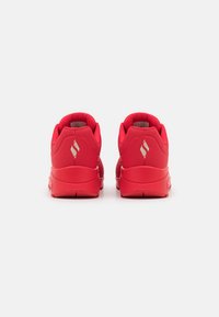Rote Sportschuhe mit einem glatten Obermaterial aus synthetischem Material, gepolstertem Kragen und Gummisohle. Verfügt über ein reflektierendes Logo an der Ferse und einen strukturierten Akzent.