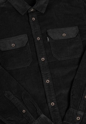 Black corduroy shirt with copper buttons, two chest pockets, pointed collar, and buttoned cuffs, featuring a soft, textured fabric.