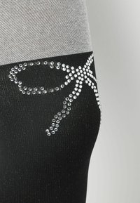 Sorte strømpebukser med en grå overdel, der har et rhinestone-mønster, som ligner en sløjfe. Glat tekstur med et subtilt skær.