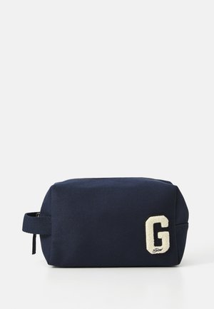 Navy cosmetic bag with a textured fabric, rectangular shape, and a zip closure, featuring a white embroidered letter "G" on the front.