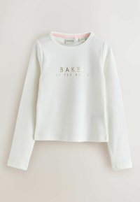 Witte langwerpige top met ribbeltextuur en een gouden opdruk "BAKER by TED BAKER" gecentreerd op de borst. Ronde halslijn, cropped fit.