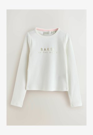 Balta garām piedurknēm blūze ar ribu rakstu un zelta uzrakstu "BAKER by TED BAKER", kas ir izvietots vidū uz krūts. Apaļa kakla izgriezums, īsāka piegriezuma forma.