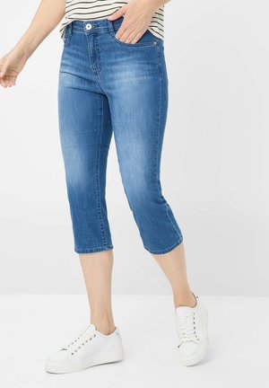 Lichtblauwe denim capri-broeken met een slim fit, vijfzakkenontwerp en omgeslagen manchetten. Gecombineerd met witte sneakers.