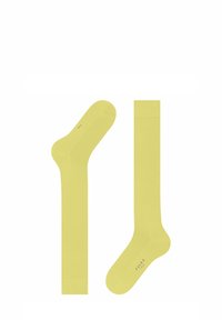 Calzini alla caviglia giallo chiaro con una texture liscia e aperture ribattute. Presentano un logo sul lato, progettati per comfort e vestibilità.