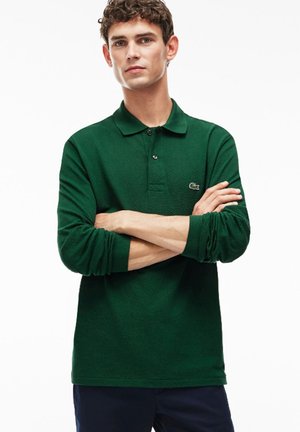 Polo de manga larga verde con una tela texturizada, cuello de dos botones y pequeño logotipo bordado en el pecho. Adecuado para uso casual.