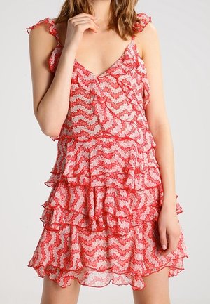 Czerwona i biała sukienka warstwowa z wzorem w zygzaki, falbankowymi ramiączkami i rozkloszowanym dołem. Przezroczysta tkanina dodaje lekkości i dynamiki.