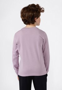 Chemise à manches longues en lavande clair, fabriquée en tissu doux avec un col rond et un design simple, présentant un ourlet droit et sans motifs visibles.