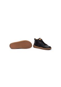 Zapatos altos de cuero negro con suela de goma color beige. Presentan cierre de cordones, costuras en contraste y una etiqueta de logo en el tobillo.