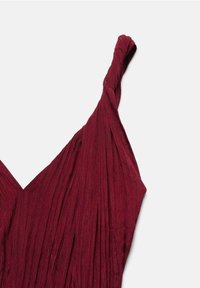 Robe bordeaux avec une bretelle torsadée et des plis verticaux, mettant en valeur une apparence texturée. Le décolleté en V accentue la silhouette.