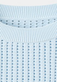 Lyseblå strikket sweater med ribstrikket krave og lodrette, åbne striber, der skaber et tekstureret mønster.