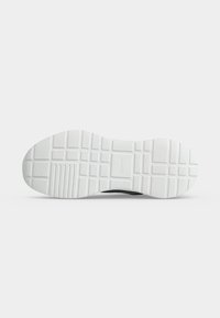 Semelle d'une chaussure blanche avec un motif de bande de roulement en grille et en lignes, présentée à plat sur un fond gris clair.