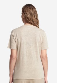 Beige kortærmet T-shirt lavet af et tekstureret, let materiale. Har en rund halsudskæring og en afslappet pasform, uden synlige mønstre eller grafikker.