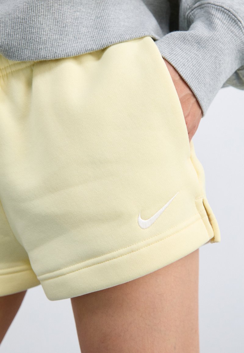 Shorts de algodón amarillo claro con un logo blanco de Nike, que cuentan con un corte relajado, dobladillo enrollado y una cintura elástica para mayor comodidad.