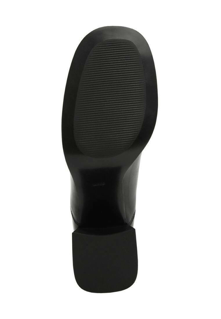 Suela de zapato negra con superficie texturizada, tacón ligeramente elevado y bordes lisos. Famosas estrías para tracción y soporte.