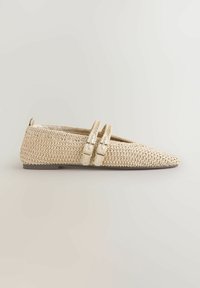 Zapato plano tejido beige con puntera puntiaguda, dos correas ajustables con hebilla y una pequeña lengüeta en la parte trasera sobre un fondo neutro.