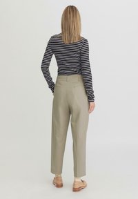 Gestreepte lange mouwen top in zwart en wit, met een op maat gemaakte, hooggetailleerde, beige broek met twee achterzakken en een zachte textuur.