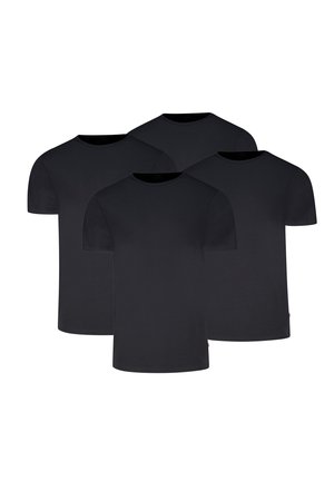 Mann trägt ein schlichtes schwarzes kurzärmeliges T-Shirt und hellgraue, eng anliegende Boxershorts, steht vor einem einfarbigen hellen Hintergrund.