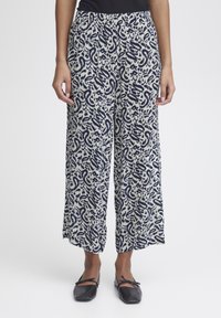 Pantalons larges en tissu crème avec un motif paisley bleu marine. Dotés d'une taille élastique et de poches latérales pour plus de commodité.