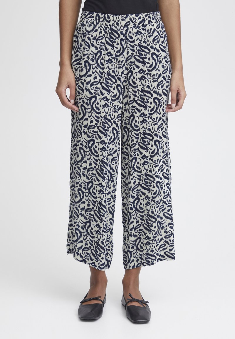 Pantalons larges en tissu crème avec un motif paisley bleu marine. Dotés d'une taille élastique et de poches latérales pour plus de commodité.