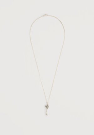 Silberne Halskette mit dünner Kette und kleinem, abstraktem Anhänger in Herzform vor schlichtem weißem Hintergrund.