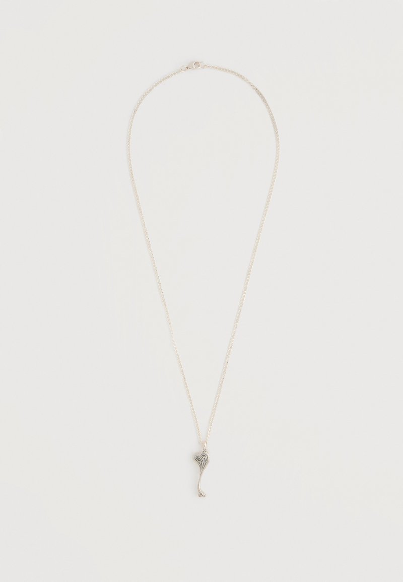 Collier en argent avec une chaîne fine et un petit pendentif abstrait en forme de cœur sur un fond blanc uni.