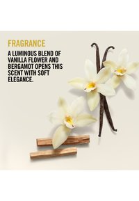Flores de vainilla, dos vainas de vainilla y dos palitos de madera dispuestos junto a un texto que describe una fragancia con notas de flor de vainilla y bergamota.