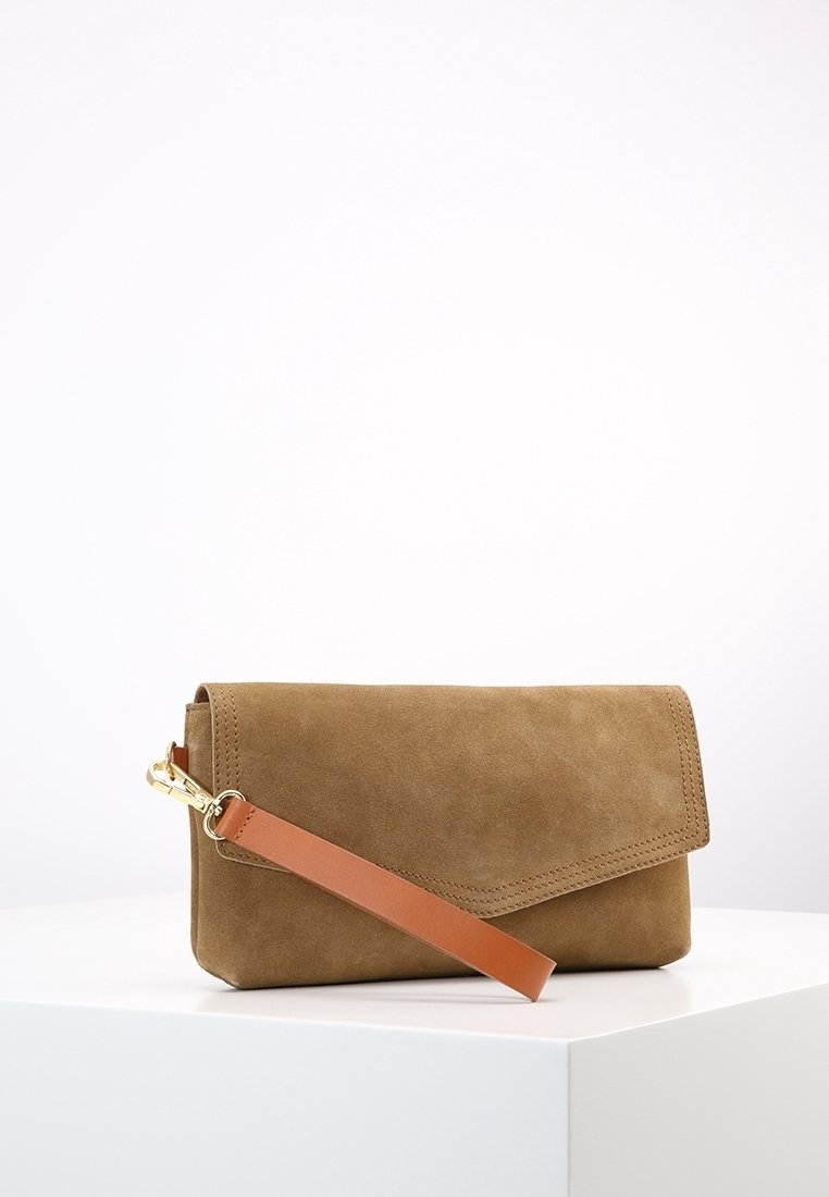 Pochette en daim marron avec une lanière de poignet en cuir beige et un fermoir doré, posée sur une plateforme blanche sur fond uni.