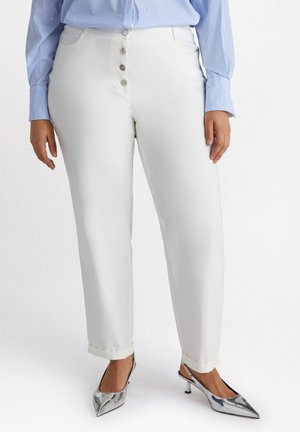 Pantalones de mezcla de algodón blancos con corte recto, con cierre de cinco botones. Combinados con unos tacones plateados de punta afilada y una camisa a rayas azules.