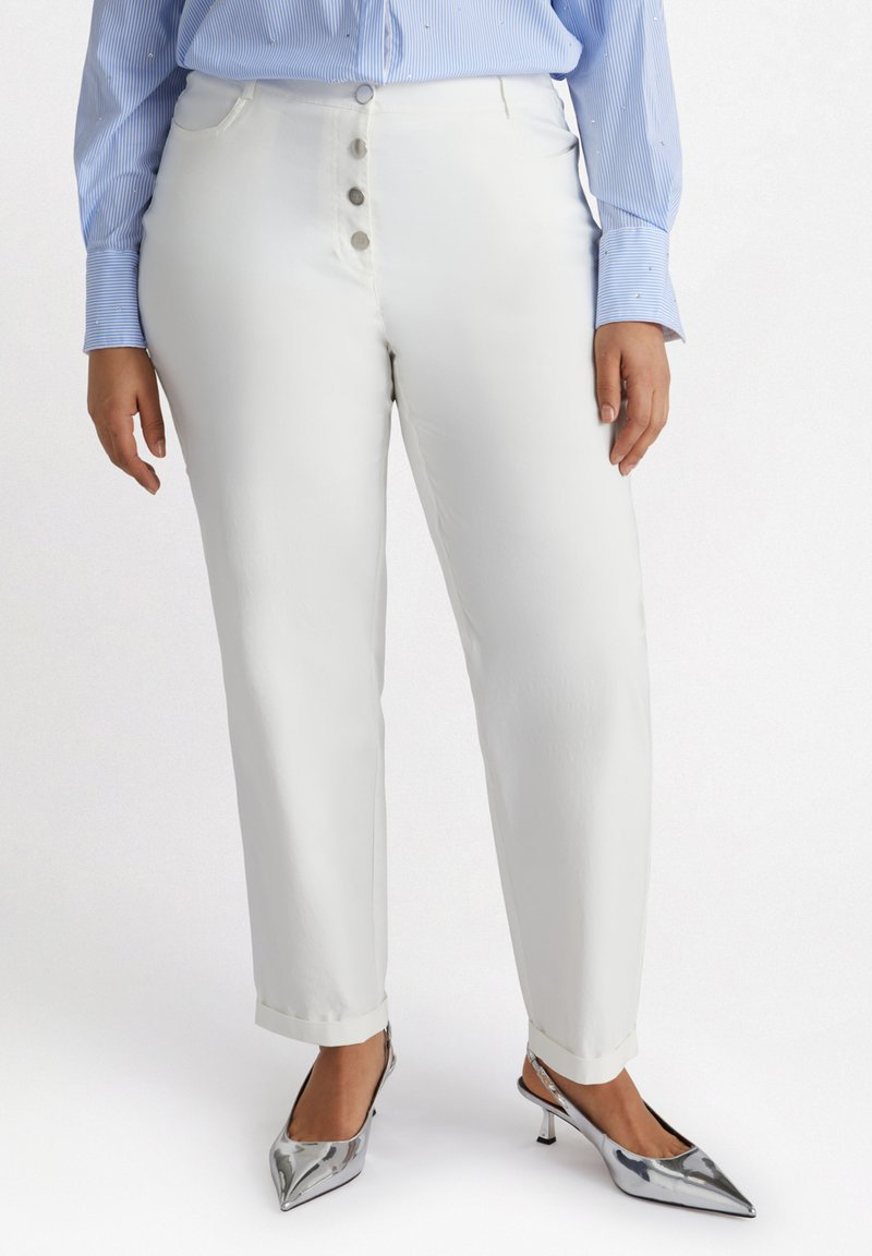 Witte katoenen broek in een rechte snit, met een sluiting van vijf knopen. Gecombineerd met zilveren puntige hakken en een blauw gestreept shirt.