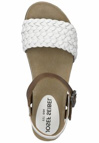 White braided upper strap with brown ankle strap and buckle, tan footbed with logo, flat sole, and rounded toe design.