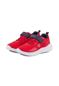 Chaussures de sport rouges avec une tige texturée, semelle en caoutchouc blanche et sangle velcro bleue. Présente un logo sur le côté et des éléments de design contrastants.