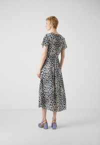 Abito lungo con maniche corte, presenta una stampa leopardata blu navy e beige. Il materiale sembra leggero, con una vita aderente e una gonna svasata.