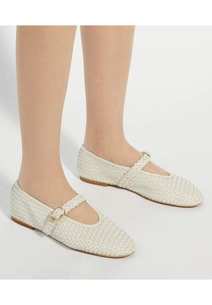 Witte geweven ballerina's met een gebogen teen, subtiele gouden hardware op een gevlochten band, en een platte bruine zool.