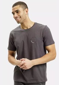 Męski ciemnoszary t-shirt bawełniany z krótkim rękawem, okrągłym dekoltem i okrągłym logo na piersi. Gładka struktura, casualowy design.