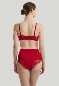 Set di reggiseno in pizzo rosso e mutande a vita alta. Presenta accenti in pizzo floreale con una fascia testurizzata e spalline regolabili.