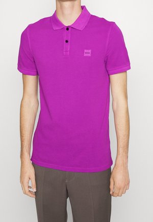 Koszulka polo z krótkim rękawem w intensywnym fioletowym kolorze, wykonana z bawełny, z dwukolorowym zapięciem na guziki, prążkowanym kołnierzem, naszywką z logo na piersi oraz gładką fakturą.