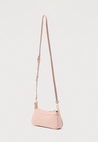 Kis babarózsaszín keresztpántos táska állítható pánttal, aranyszínű cipzárral és kapoccsal, egyszerű világos háttér előtt bemutatva.